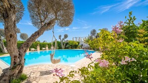 A swimming pool surrounded by stone tiles, trees, and flowering plants. - Villa Lisa with huge Pool and Garden, Melendugno, Italy (Melendugno)