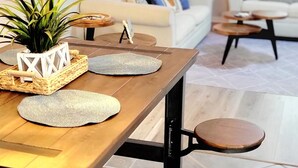 Un coin repas avec une table en bois, des tabourets et une plante en pot.