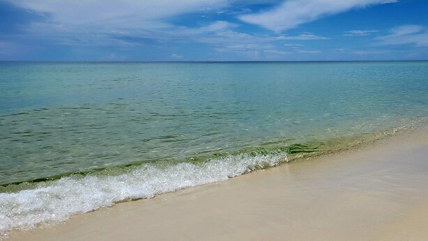 Une plage à l’eau turquoise et limpide, bordée d’un rivage sablonneux.