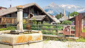A rustic building with a stone well, wooden fence, and a mountain backdrop. - Studio Placide Mountain View, Sauze d'Oulx, Italy (Sauze d'Oulx)