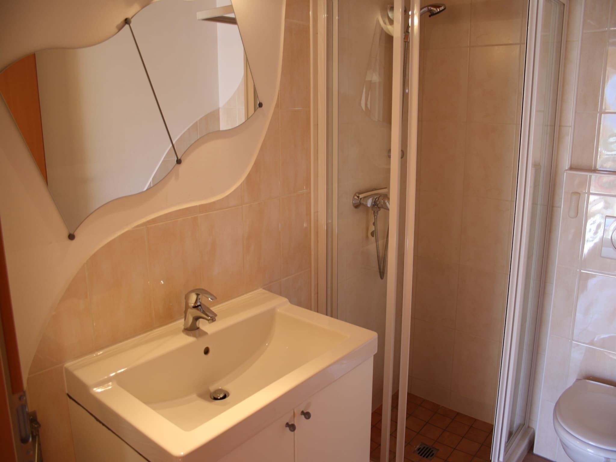 A bathroom with a sink, mirror, shower, and toilet.