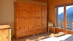 A wooden room with a large wardrobe, a bed, and a window with a view of mountains. - Tourbillon B 31 by Interhome (Ovronnaz)