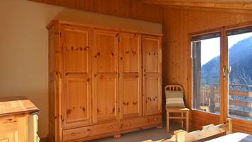 Une pièce en bois avec une grande armoire, un lit et une fenêtre donnant sur les montagnes.