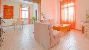 Ein Wohnzimmer mit Sofa, Couchtisch und Kamin. Es gibt einen Essbereich mit Tisch und Stühlen.