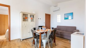 Ein Essbereich mit Holztisch und -stühlen, einer Vitrine mit Glastüren, einer Couch und einem Gemälde an der Wand.