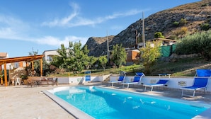 Ein Swimmingpool mit Liegestühlen, einer Pergola und einer Terrassenanlage mit Tischen und Stühlen.