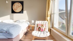 A hotel room with a bed, a chair, a nightstand, and a window with curtains. - Luxury Pool Villa in Sosoye (Sosoye)