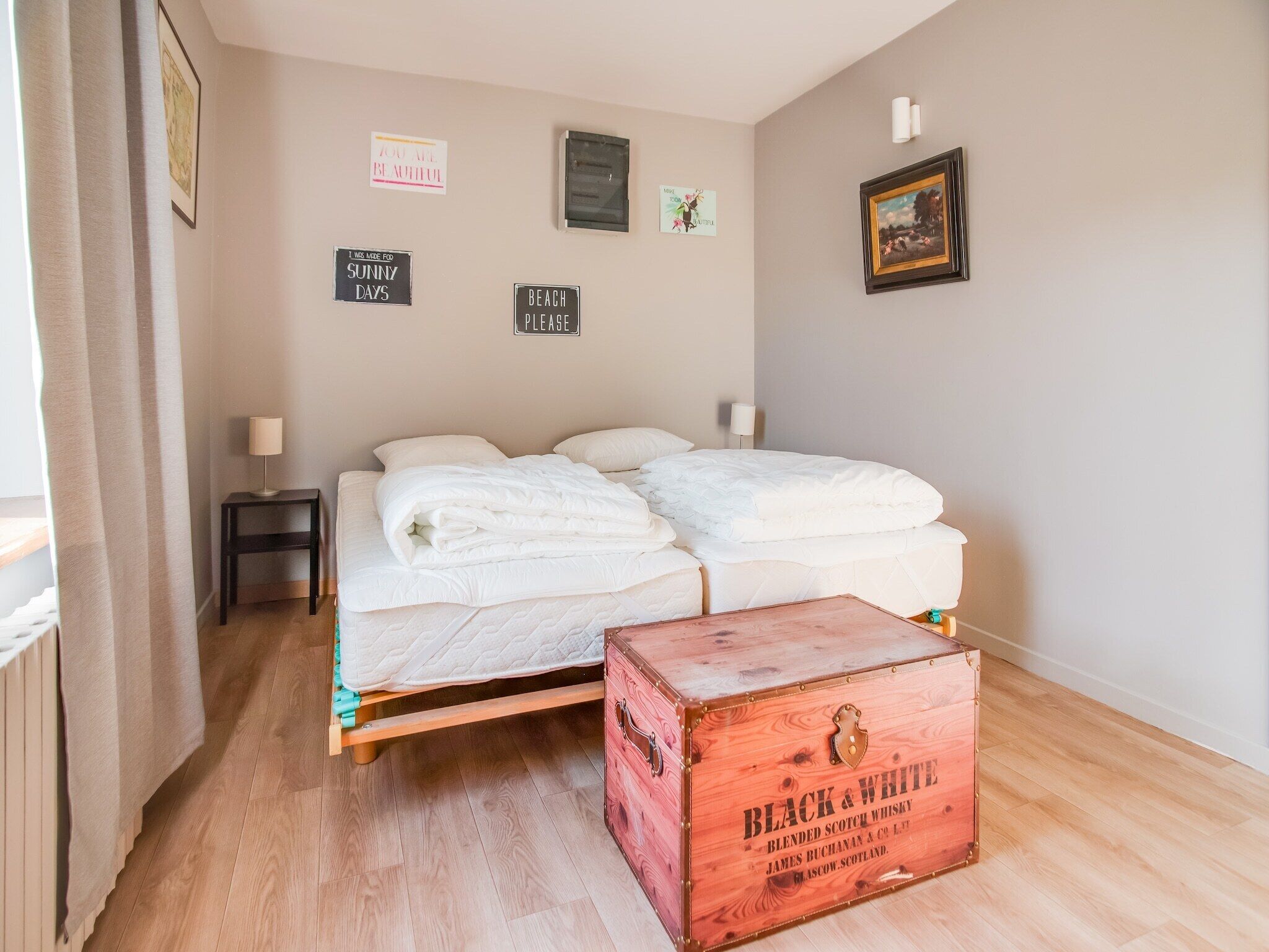 Un dormitorio con una cama de madera, una mesita de noche, un aparador y una pared decorada con letreros motivacionales.