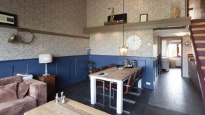 Un salon chaleureux avec un canapé, une table en bois et un coin repas comprenant une table et des chaises.