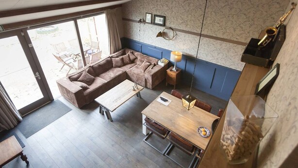 Un vaste espace de vie comprenant un canapé marron, une table basse en bois et une table à manger.