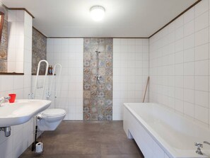 Une salle de bain comprenant des toilettes, un lavabo, une baignoire et un espace douche.