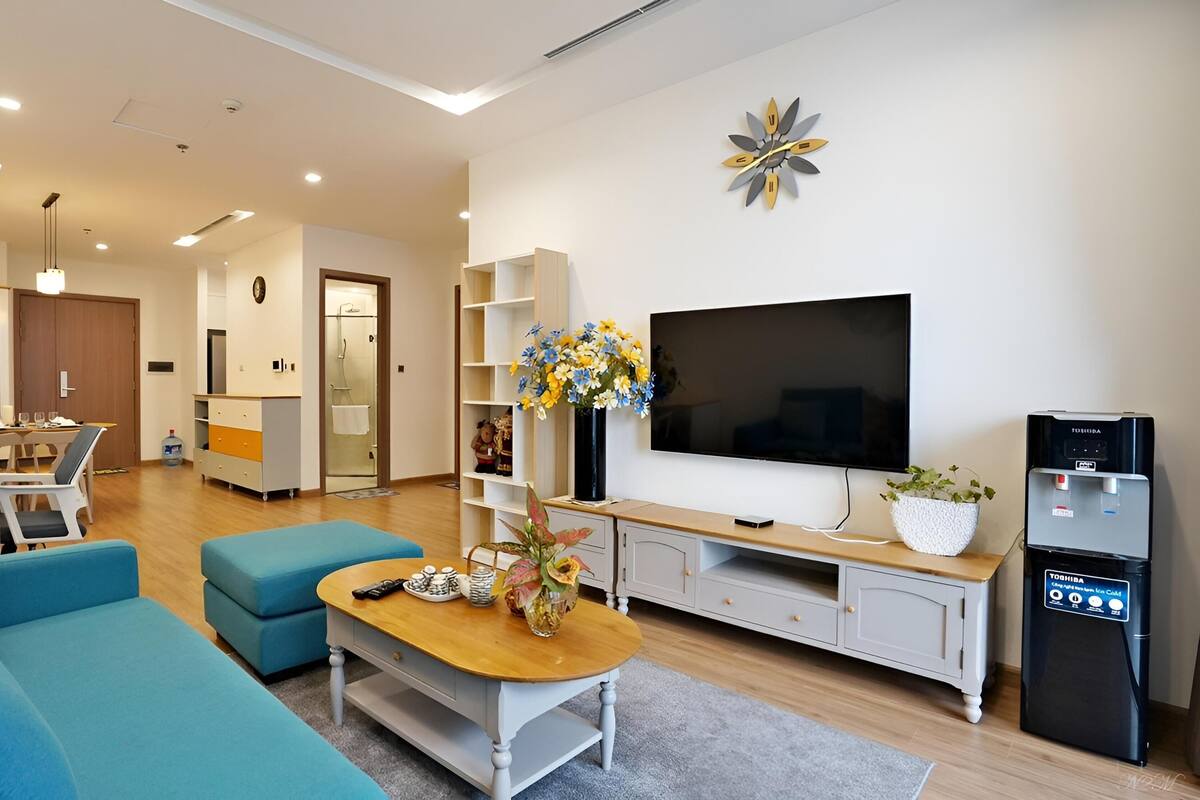 A modern living room with a sofa, coffee table, TV, and water dispenser.