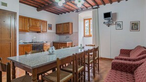 Une cuisine dotée de meubles en bois, d’un plan de travail en granit et d’un coin repas avec une table et des chaises.