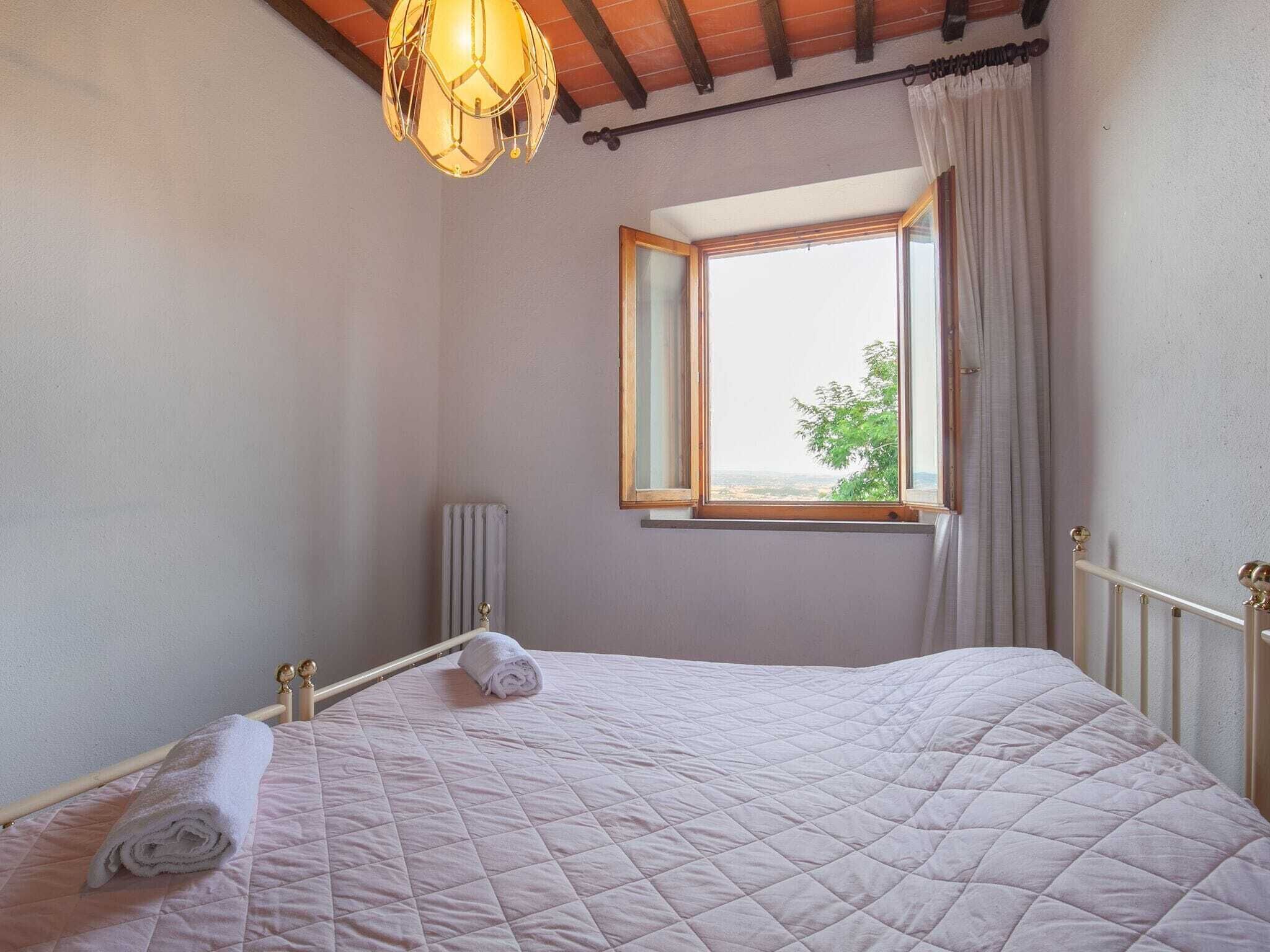 Une chambre à coucher avec un lit, une fenêtre, un radiateur et un luminaire suspendu.