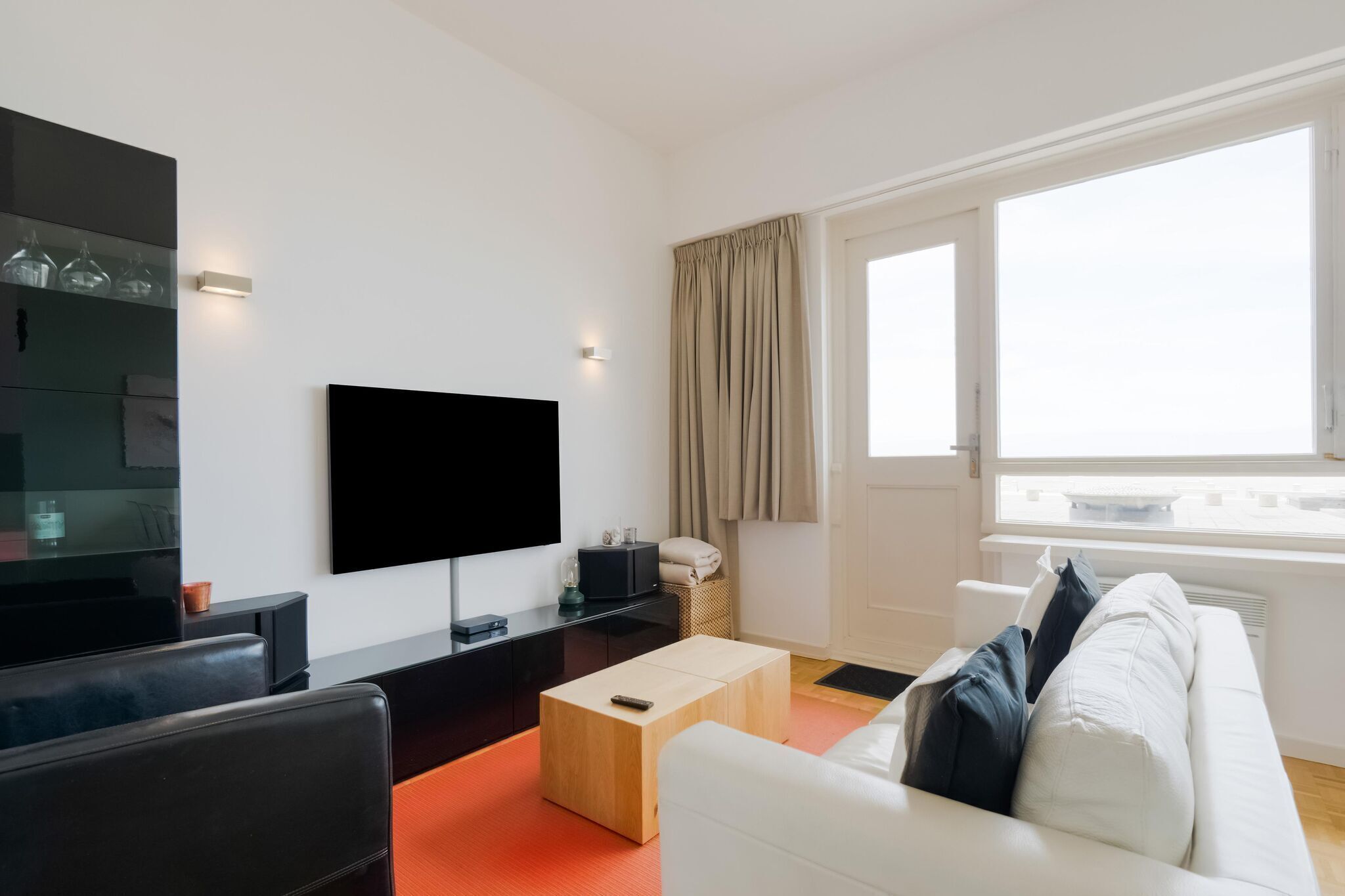 A modern living room with a flat-screen TV, a white sofa, and a wooden coffee table.