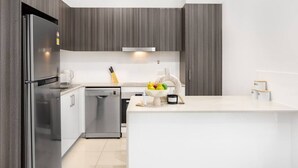 Eine moderne Küche mit einem Edelstahl-Kühlschrank, einer Spülmaschine und einer weißen Arbeitsplatte.