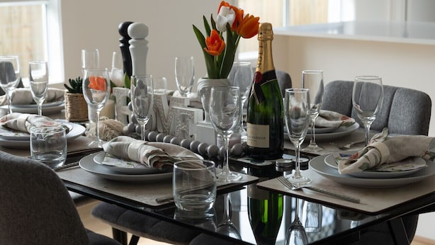 A dining table set with multiple wine glasses, plates, and a bottle of champagne. - Brand-new 4BR modern family home @Park Ridge (Park Ridge)