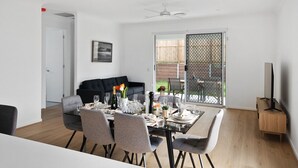 A dining area with a table set for six, a black sofa, and a TV stand. - Brand-new 4BR modern family home @Park Ridge (Park Ridge)