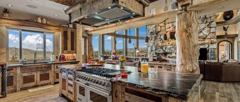 A spacious kitchen with a large island, wooden cabinetry, and a stone wall.