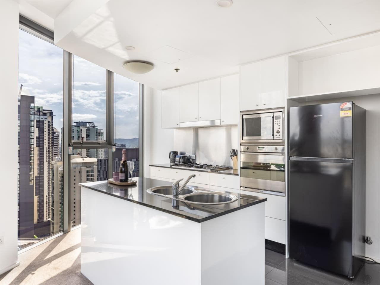 A modern kitchen with a large island, stainless steel appliances, and a view of the city.