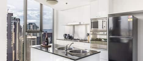 A modern kitchen with a large island, stainless steel appliances, and a view of the city.