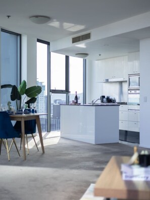 A modern kitchen with white cabinetry, a central island, and a dining area with a table and chairs.