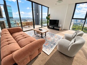 A modern living room with a sofa, armchair, and a flat-screen TV.