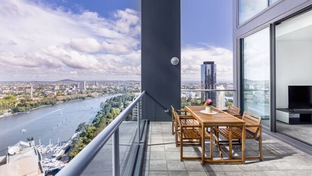 A balcony with a table and chairs, overlooking a river and cityscape. - 2BR Apt in the Heart of the City w/ Stunning View (Brisbane City)