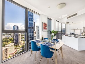 A modern dining area with a city view, a kitchen, and a large window.