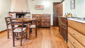 A rustic kitchen with wooden furniture, a fireplace, and a wooden ceiling.