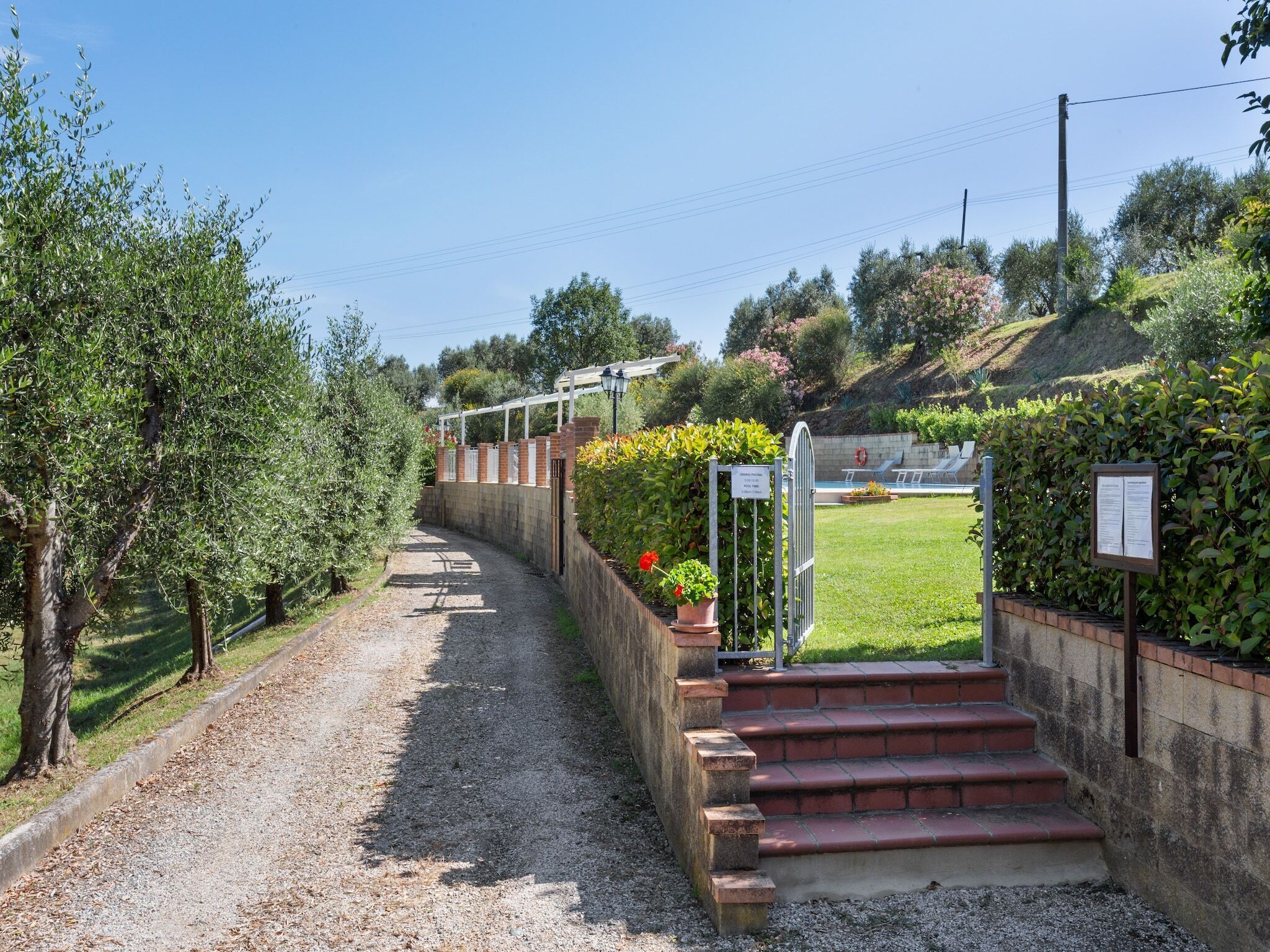 A gravel path leading to a pool area with steps and a pergola.