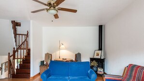 A living room with a blue sofa, a wooden coffee table, a striped armchair, a fireplace, and a staircase.