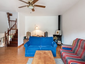 A living room with a blue sofa, a wooden coffee table, a striped armchair, a fireplace, and a staircase. - Pet-Friendly Getaway (Loredo)