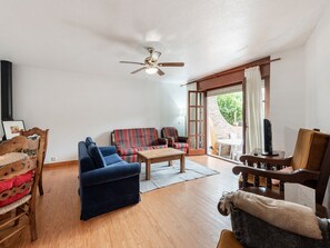 A living room with a sofa, armchairs, a coffee table, and a ceiling fan.