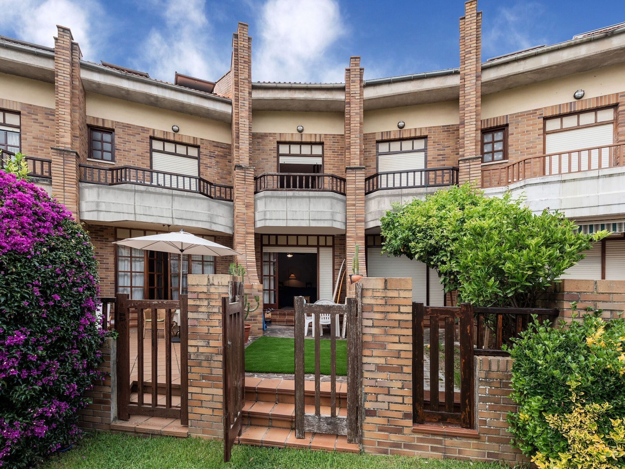 A multi-story building with brick exterior, balconies, and a gated entrance.