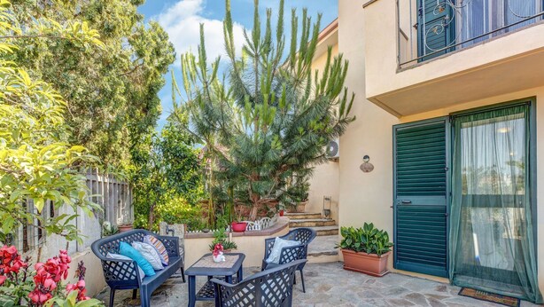 A patio with outdoor furniture, a stone floor, and potted plants.