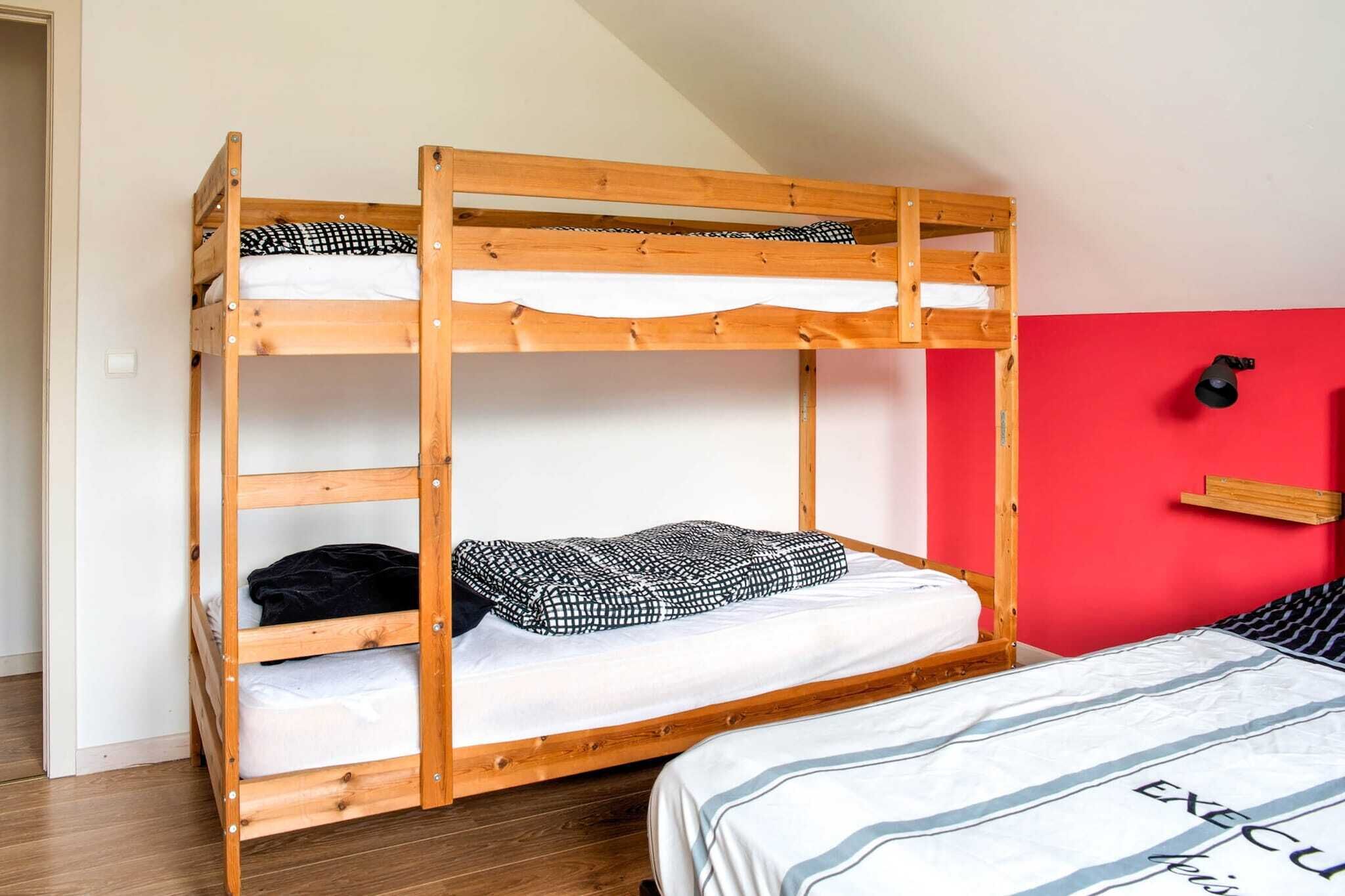 Ein Etagenbett mit roter Wand und einer schwarzen Wandleuchte.