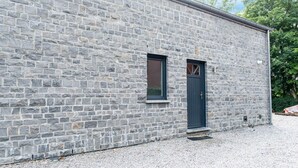 Ein Steinhaus mit einer dunklen Tür und einem kleinen Fenster.