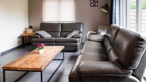 Ein modernes Wohnzimmer mit einem braunen Ledersofa, einem Holztisch und einem grauen Sofa.