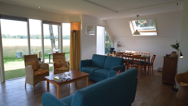 A spacious living room with a large sofa, a coffee table, and a dining area with chairs and a table.