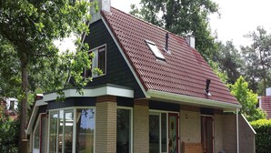 A house with a sloped roof, large glass windows, and a brick exterior.