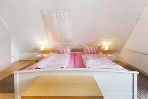 A bedroom with a bunk bed, two bedside lamps, a window with a curtain, and a radiator.