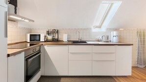 A modern kitchen with a built-in oven, microwave, and coffee maker, featuring a skylight and a wooden countertop. - Apartment 'Haus Am Südhang' with Shared Garden, Balcony and Wi-Fi (Lenzkirch)