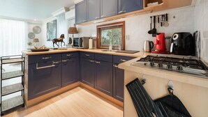 A modern kitchen with dark blue cabinets, a wooden countertop, a gas stove, and various kitchen appliances. - Holiday Home in Garderen by Veluwe (Garderen)