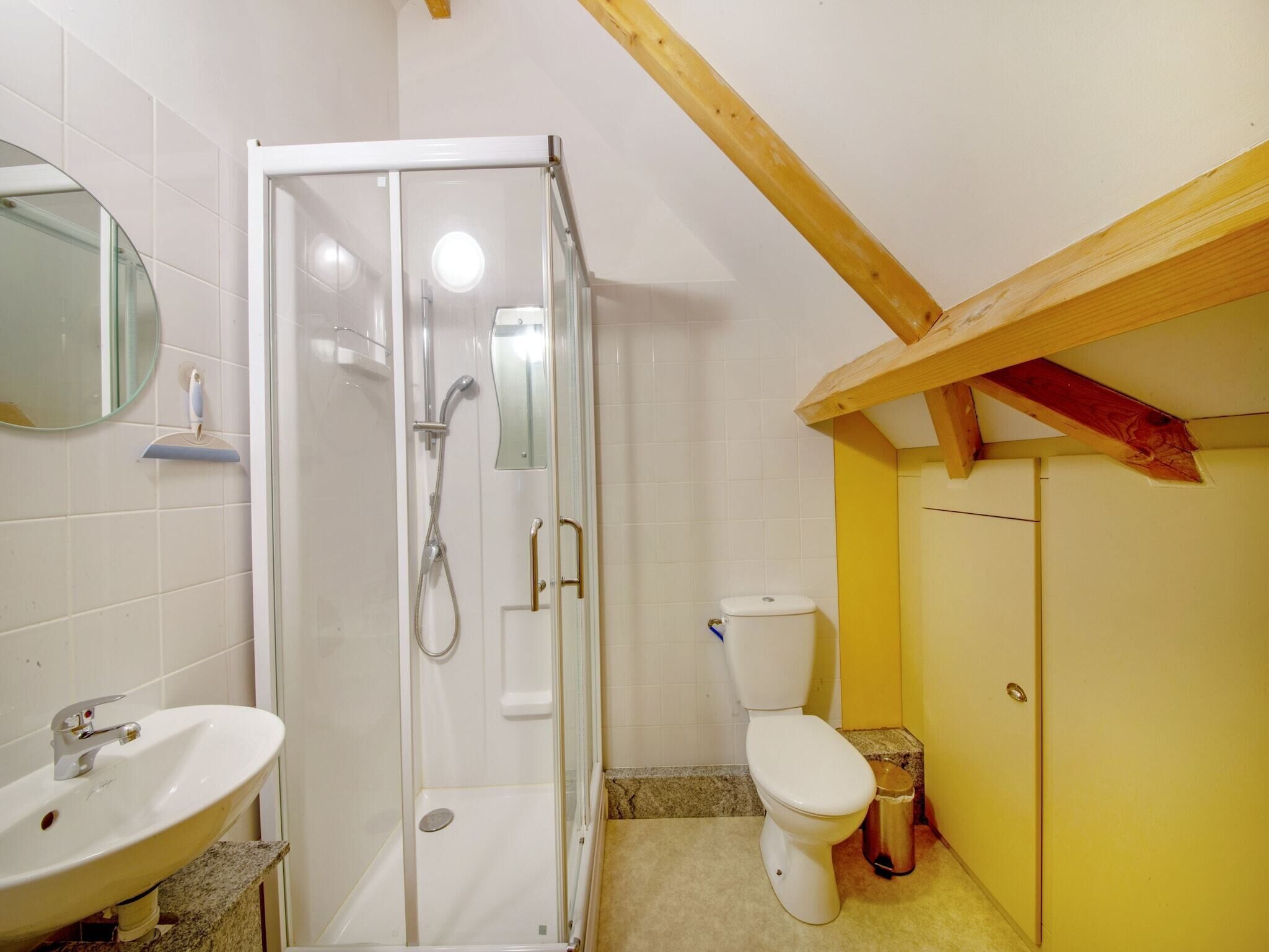 A bathroom with a glass shower enclosure, a white toilet, and a sink with a marble countertop.