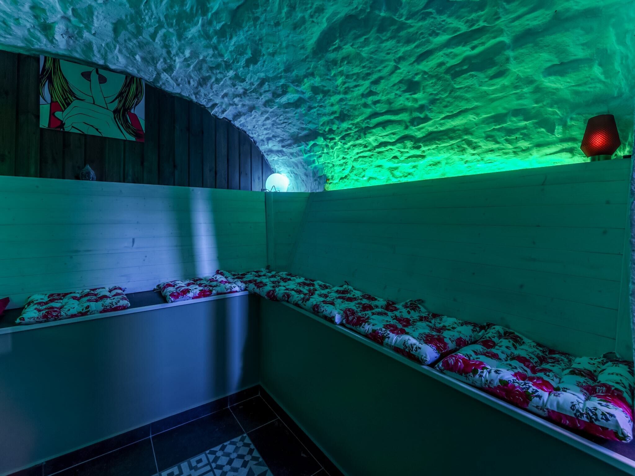 A sauna with wooden benches and a green-lit ceiling.