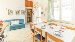 Una cocina luminosa con una mesa de comedor preparada para cuatro personas, un sofá azul y un armario de madera.