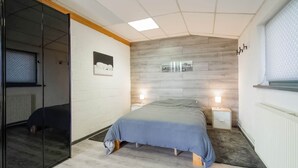 A modern bedroom with a bed, bedside tables, a wardrobe, and a wall-mounted shelf. - Cottage in Vaux-sur-Sûre with garden (Vaux-sur-Sûre)