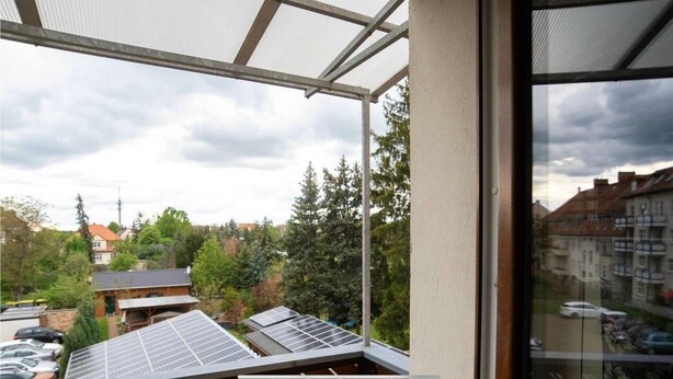 A balcony with solar panels, a view of a residential area, and a building with a sloped roof. - Apartment 'Moderne Ferienwohnung In Der Stadt' with Balcony and Wi-Fi (Forst/Lausitz)