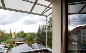 Un balcon doté de panneaux solaires, une vue sur un quartier résidentiel et un bâtiment avec un toit en pente.